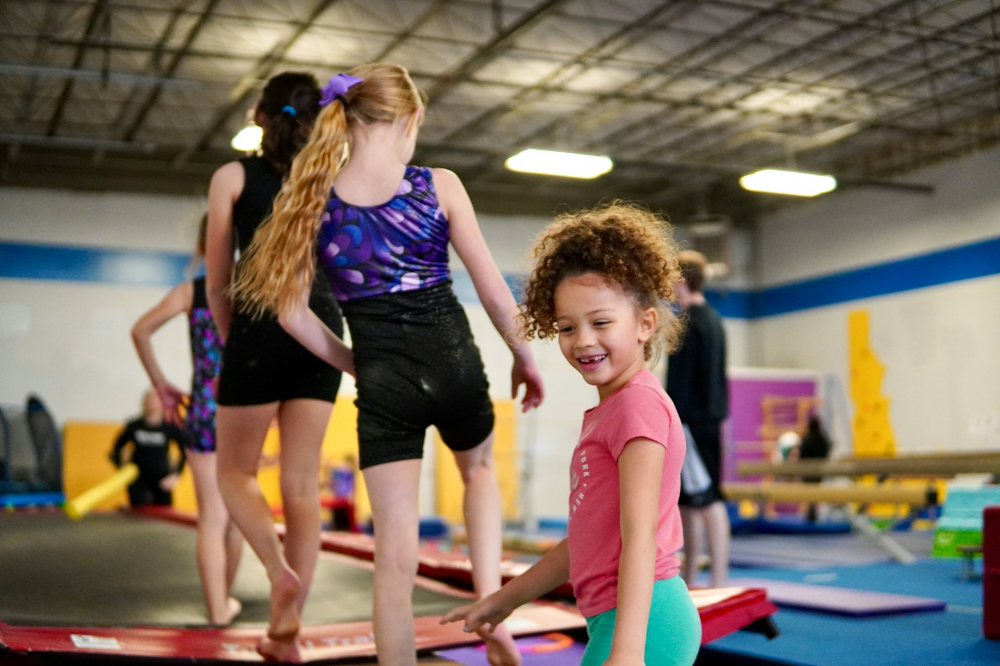 Young girl smiles while standing in a gymnastics gym.