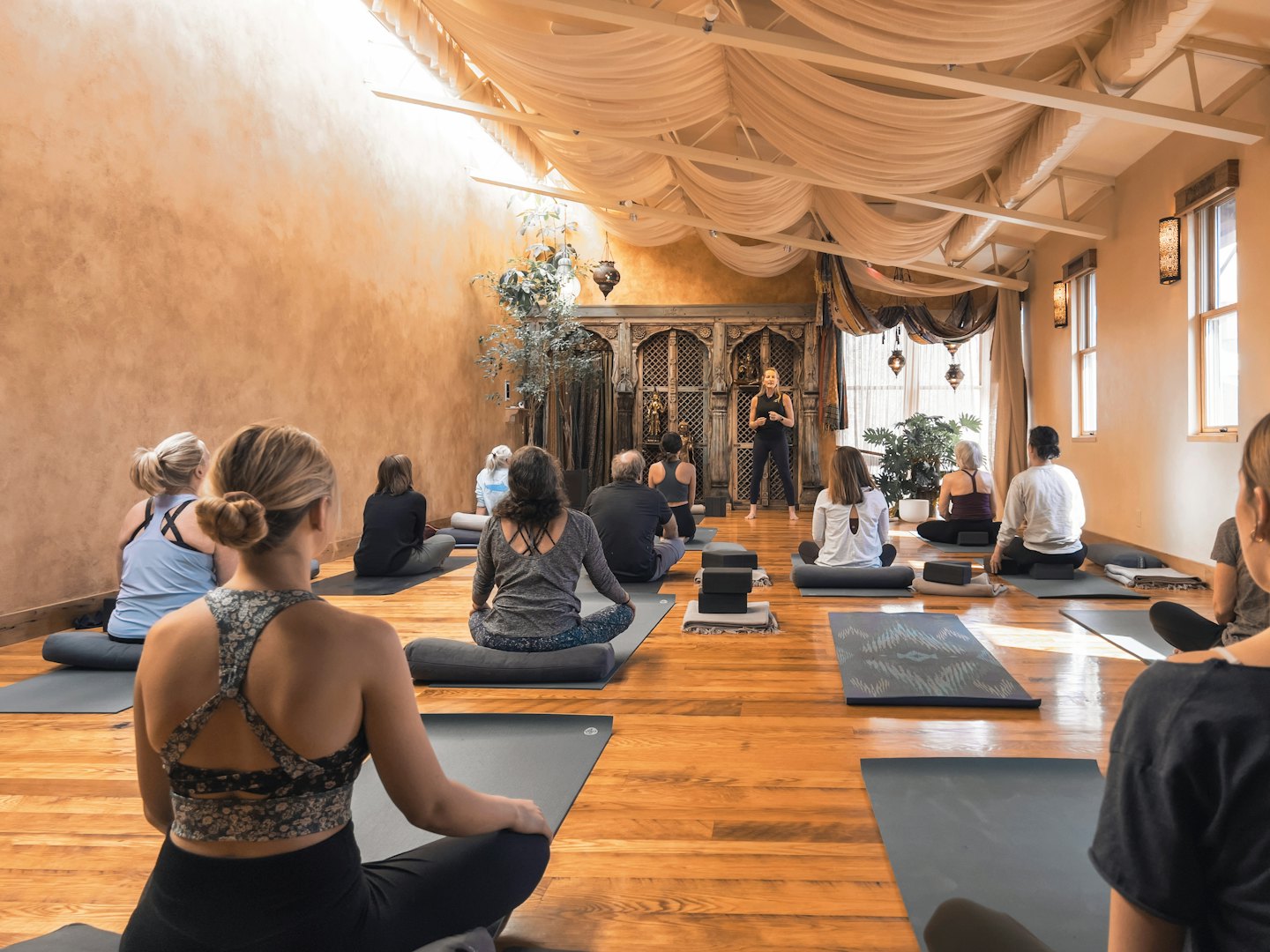 Instructor leads diverse adults in a yoga class.
