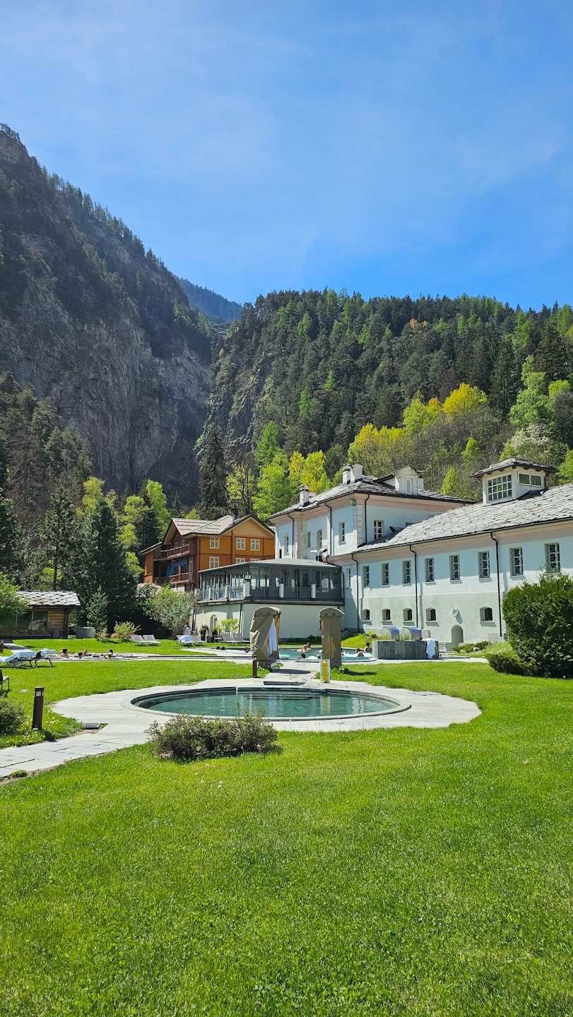 Guests relax in outdoor pools at a mountain resort.