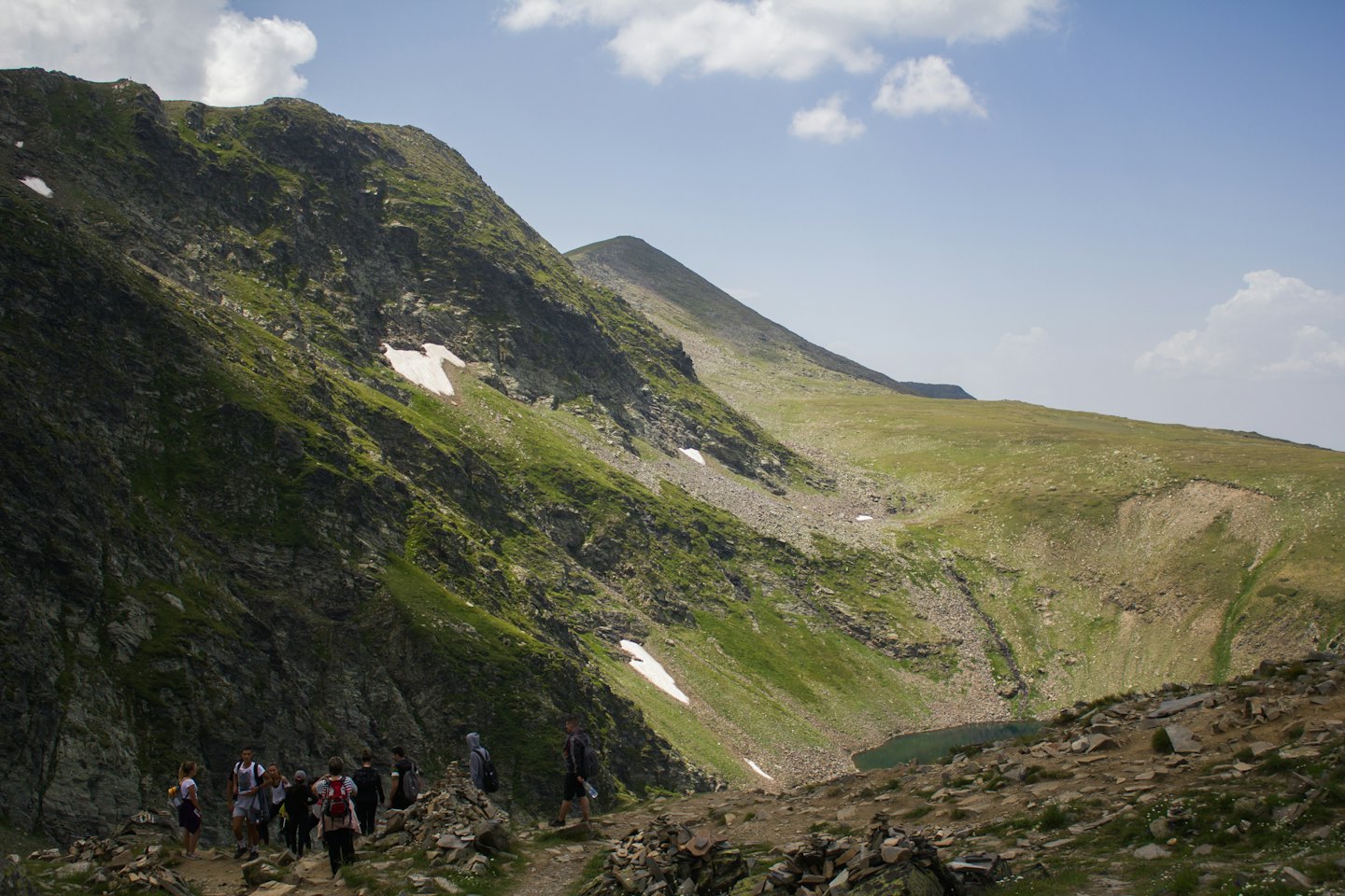 Hikers with backpacks climb a steep rocky mountain trail.